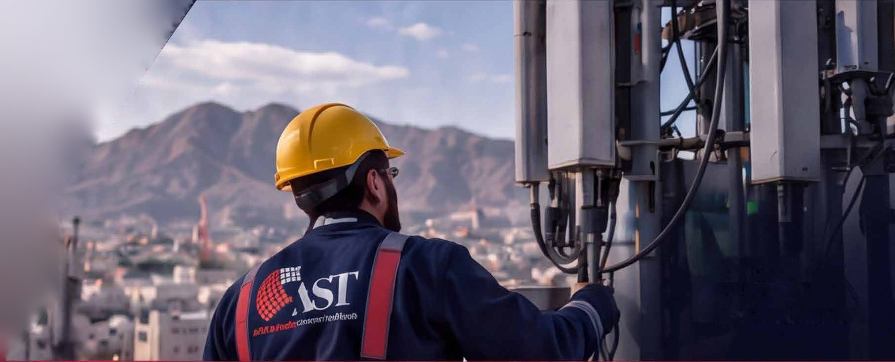 AST engineer at a rooftop telecom site facing the Hajar mountains