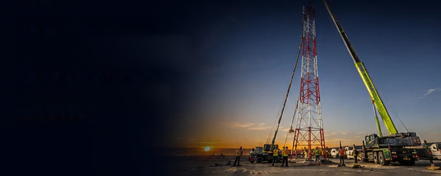 Cranes lifting a relocated telecom tower at sunset