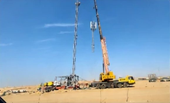 Crane lifting a telecom tower section in the NEOM desert